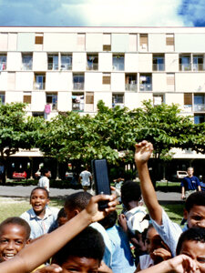 Housing building and children cheering in front of it